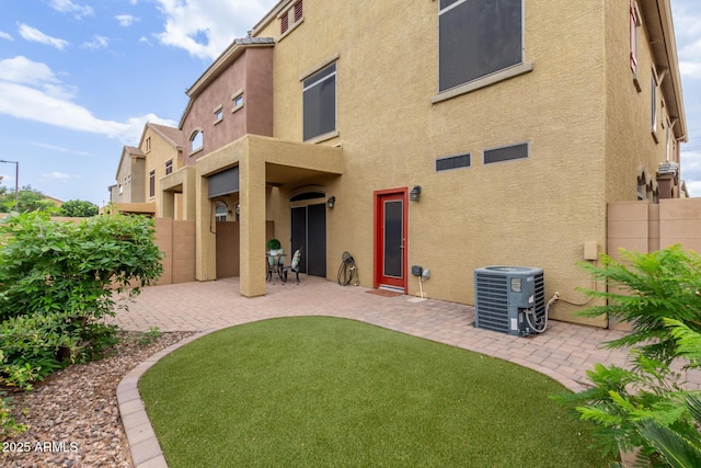 back of property with stucco siding, a patio area, central air condition unit, and a fenced backyard