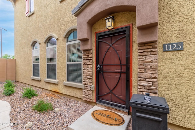 doorway to property featuring stone siding and stucco siding