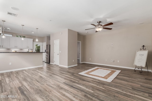 unfurnished living room with wood finished floors, a ceiling fan, and baseboards