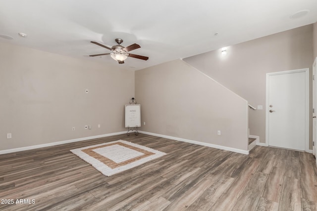 unfurnished living room with ceiling fan, wood finished floors, stairs, and baseboards
