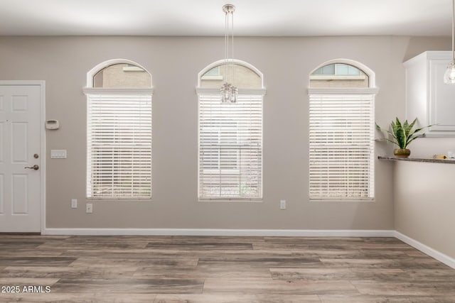 unfurnished dining area featuring wood finished floors and baseboards
