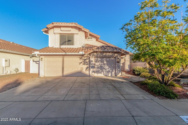 mediterranean / spanish-style house with a tiled roof, concrete driveway, fence, and stucco siding