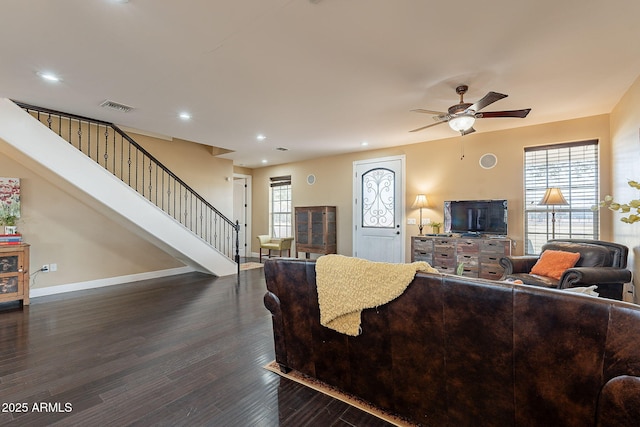 living room with dark wood-type flooring, ceiling fan, and plenty of natural light