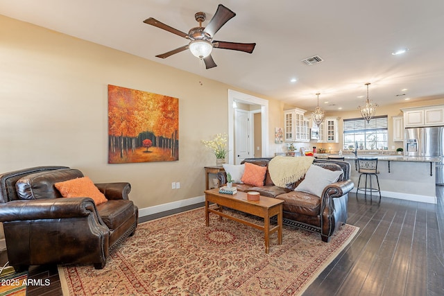 living room with dark hardwood / wood-style flooring and ceiling fan with notable chandelier