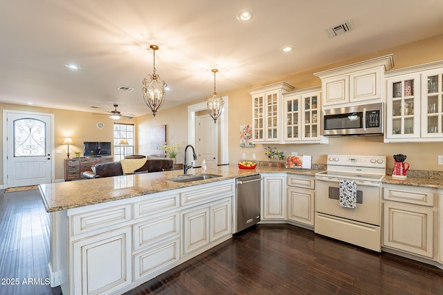 kitchen featuring sink, dark wood-type flooring, hanging light fixtures, stainless steel appliances, and kitchen peninsula