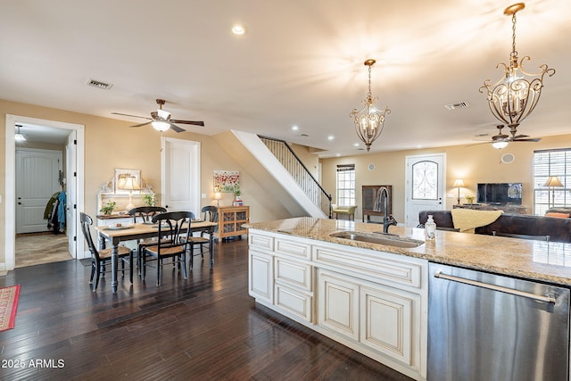 kitchen with pendant lighting, sink, dishwasher, light stone counters, and dark hardwood / wood-style flooring