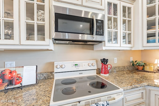 kitchen featuring white electric stove, white cabinetry, and light stone counters