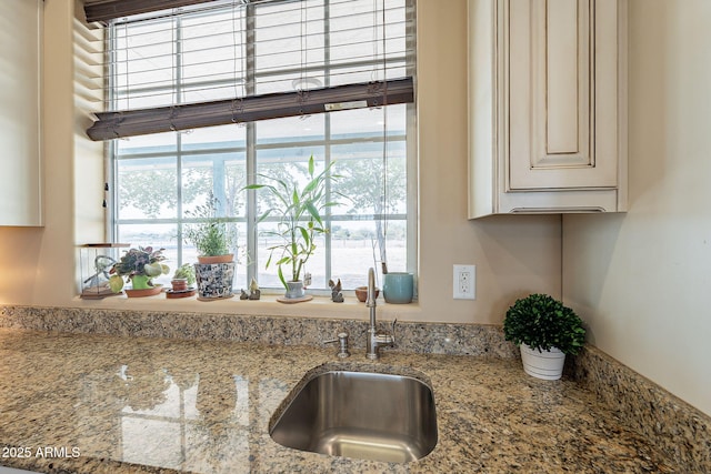 kitchen with sink, a wealth of natural light, and light stone counters