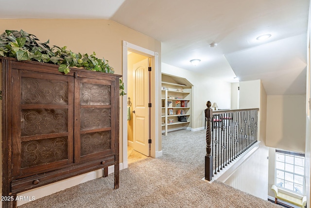 hallway with light colored carpet and lofted ceiling