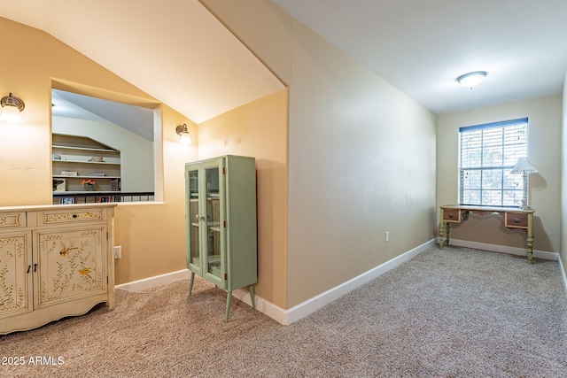 interior space featuring built in shelves, lofted ceiling, and carpet floors