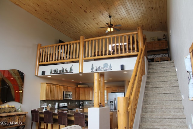 stairs featuring high vaulted ceiling, a ceiling fan, and wooden ceiling