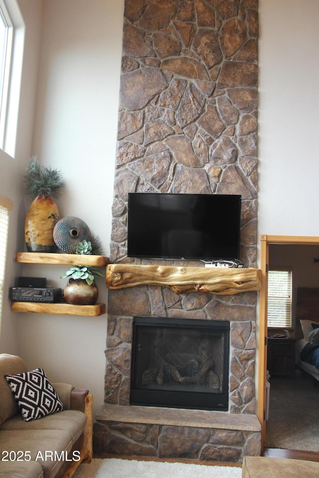interior details featuring a stone fireplace and carpet floors