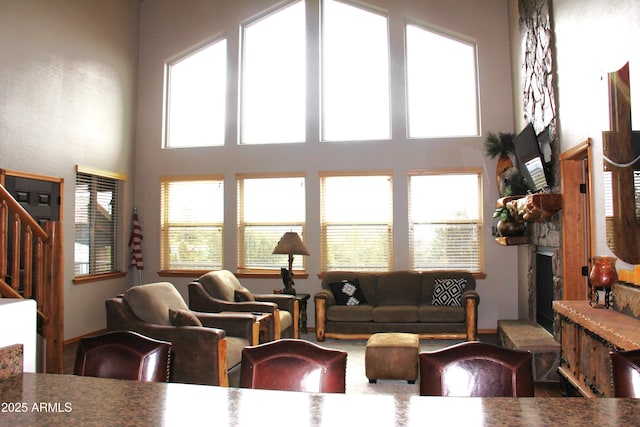 living area featuring stairs, a towering ceiling, and a healthy amount of sunlight