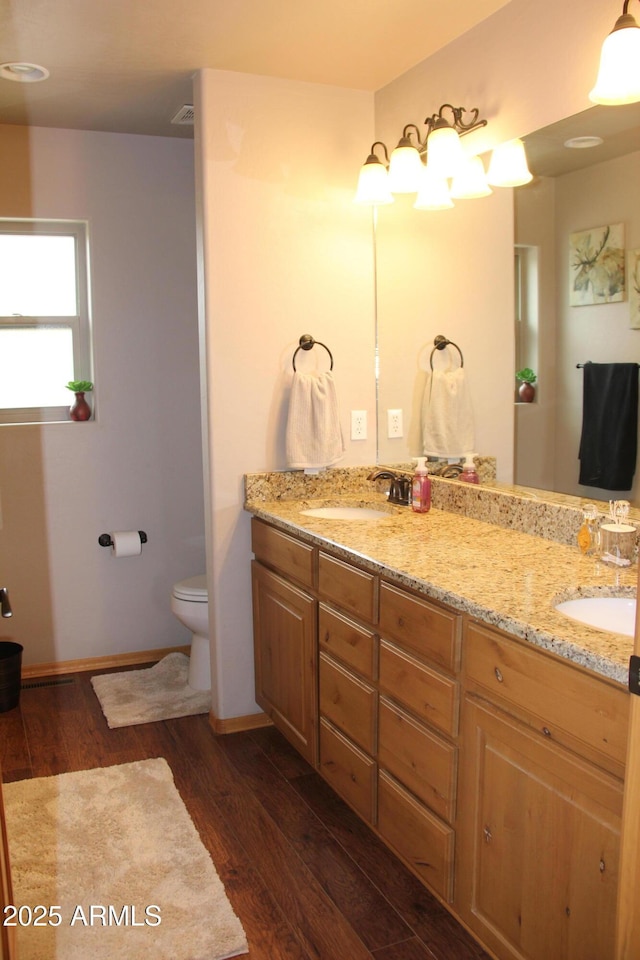 full bath with double vanity, a sink, and wood finished floors