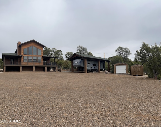 view of front of property featuring an outdoor structure, a chimney, a shed, a wooden deck, and a garage