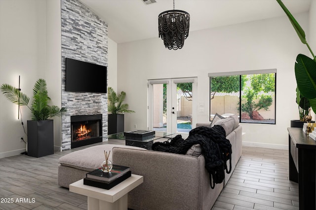 16238 N 58th St, Scottsdale, AZ 85254 - living area with light wood finished floors, a chandelier, a stone fireplace, french doors, and a towering ceiling