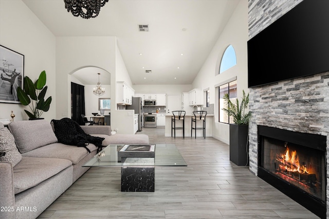 16238 N 58th St, Scottsdale, AZ 85254 - living area featuring a chandelier, high vaulted ceiling, a fireplace, light wood-style flooring, and arched walkways