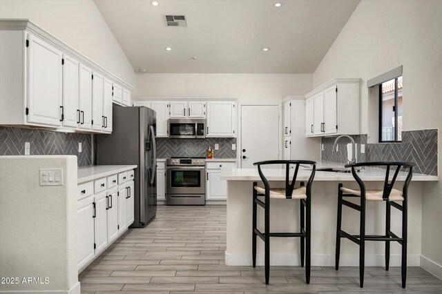 16238 N 58th St, Scottsdale, AZ 85254 - kitchen featuring stainless steel appliances, vaulted ceiling, a peninsula, backsplash, and white cabinets