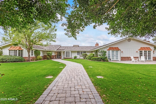 view of front of home featuring brick siding, french doors, and a front lawn