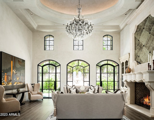 living room with a healthy amount of sunlight, hardwood / wood-style floors, a towering ceiling, and a notable chandelier