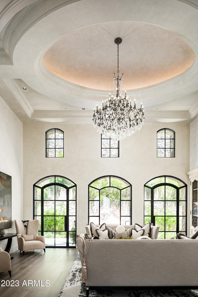 living room with a healthy amount of sunlight, a towering ceiling, and hardwood / wood-style flooring