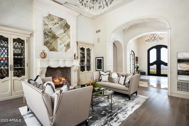 living room with a high ceiling, dark wood-type flooring, french doors, and a notable chandelier