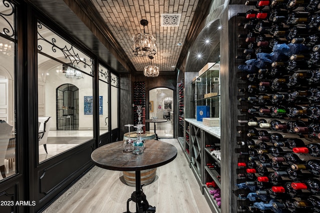 wine cellar featuring brick ceiling, light hardwood / wood-style floors, and an inviting chandelier