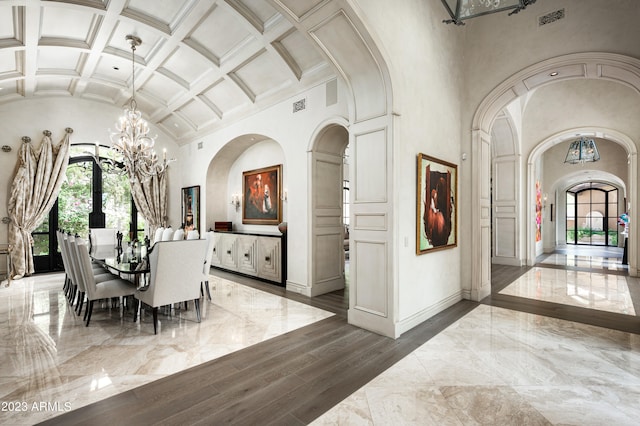 dining space with coffered ceiling, beamed ceiling, hardwood / wood-style floors, and a high ceiling