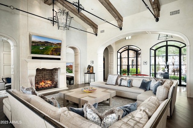 living room featuring beamed ceiling, hardwood / wood-style flooring, a chandelier, and high vaulted ceiling