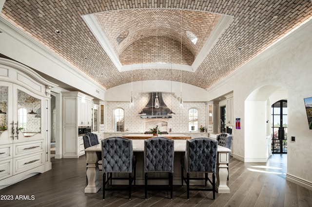 kitchen featuring vaulted ceiling, pendant lighting, ventilation hood, crown molding, and dark hardwood / wood-style floors