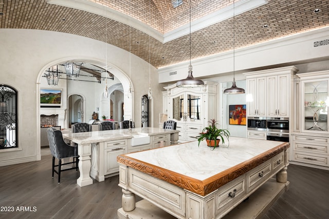 kitchen featuring dark wood-type flooring, white cabinetry, hanging light fixtures, a kitchen island, and high vaulted ceiling