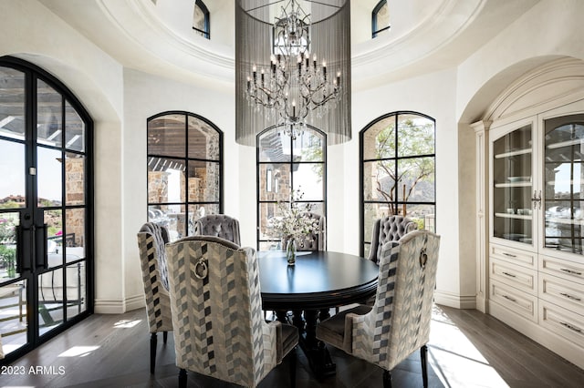 dining space featuring a raised ceiling, a high ceiling, dark hardwood / wood-style floors, and a notable chandelier