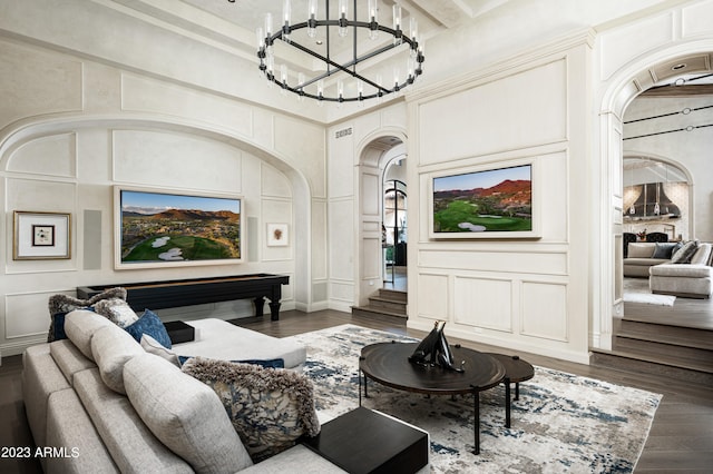 living room featuring a notable chandelier, a high ceiling, a fireplace, and dark wood-type flooring