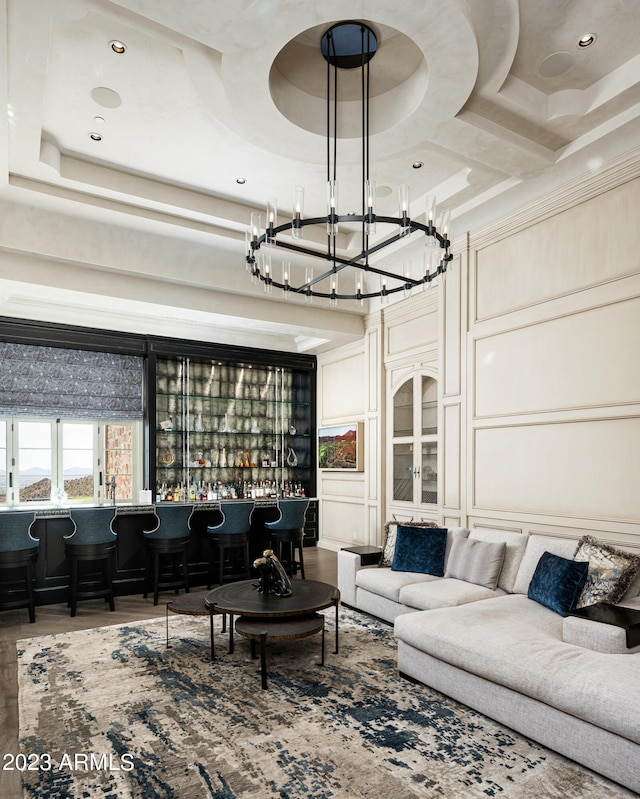 living room featuring an inviting chandelier, coffered ceiling, and bar