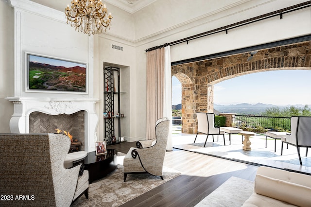 living room with a mountain view, a notable chandelier, a fireplace, crown molding, and hardwood / wood-style floors