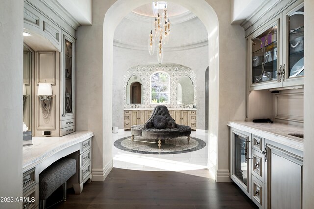 interior space featuring light stone counters, pendant lighting, beverage cooler, dark wood-type flooring, and a notable chandelier