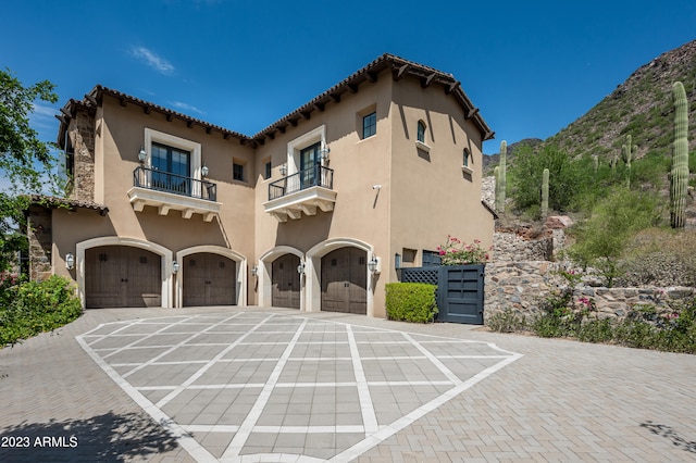 mediterranean / spanish-style home featuring a balcony, a mountain view, and a garage