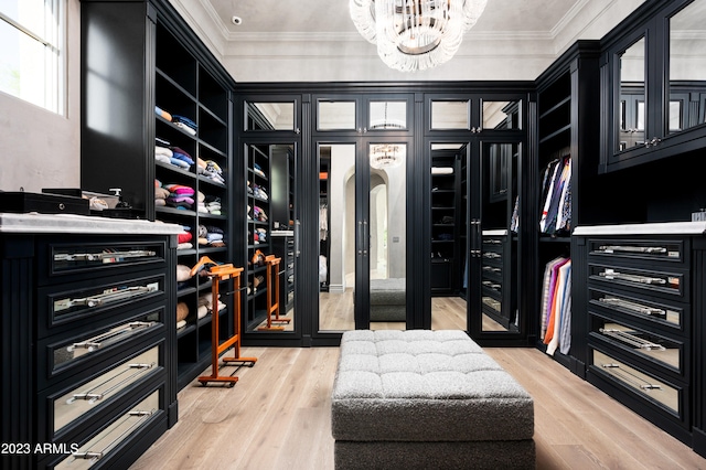 walk in closet featuring light wood-type flooring and a chandelier