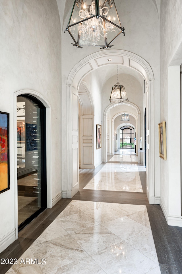 hallway featuring an inviting chandelier, dark wood-type flooring, and a high ceiling