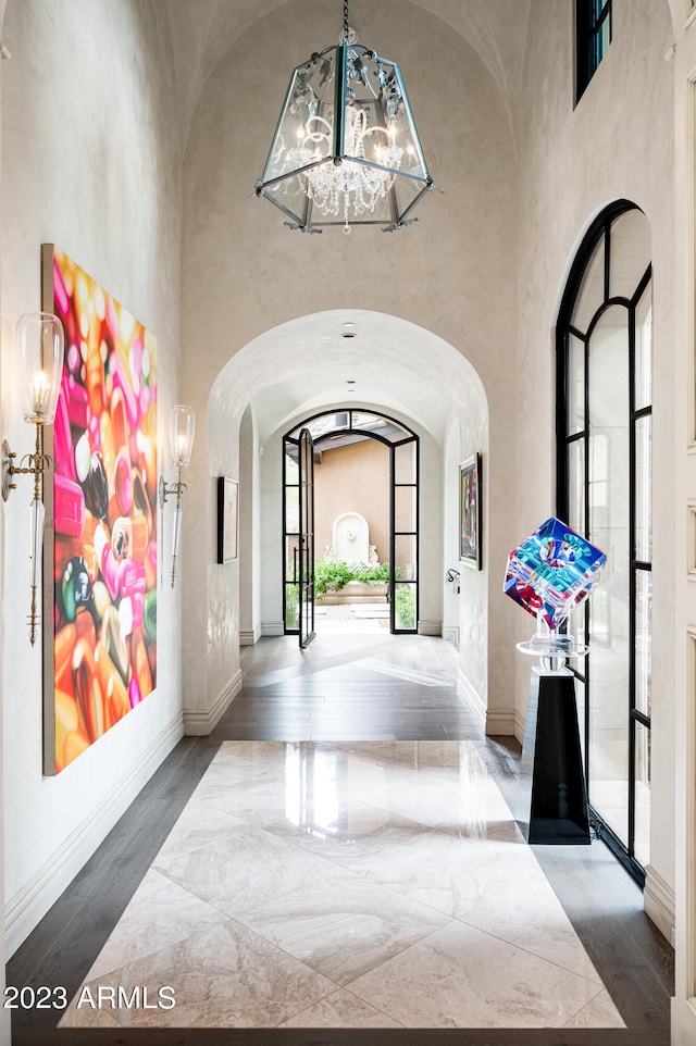 interior space featuring wood-type flooring, a chandelier, and high vaulted ceiling