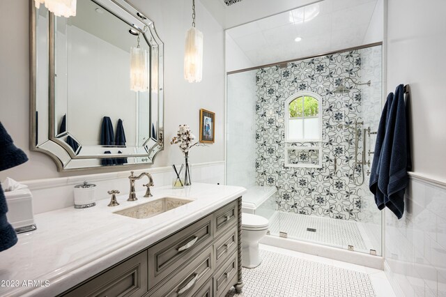 bathroom with a tile shower, vanity, toilet, and tile patterned floors