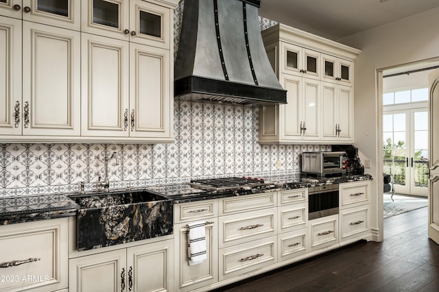 kitchen featuring custom range hood, dark stone counters, cream cabinets, and dark hardwood / wood-style floors