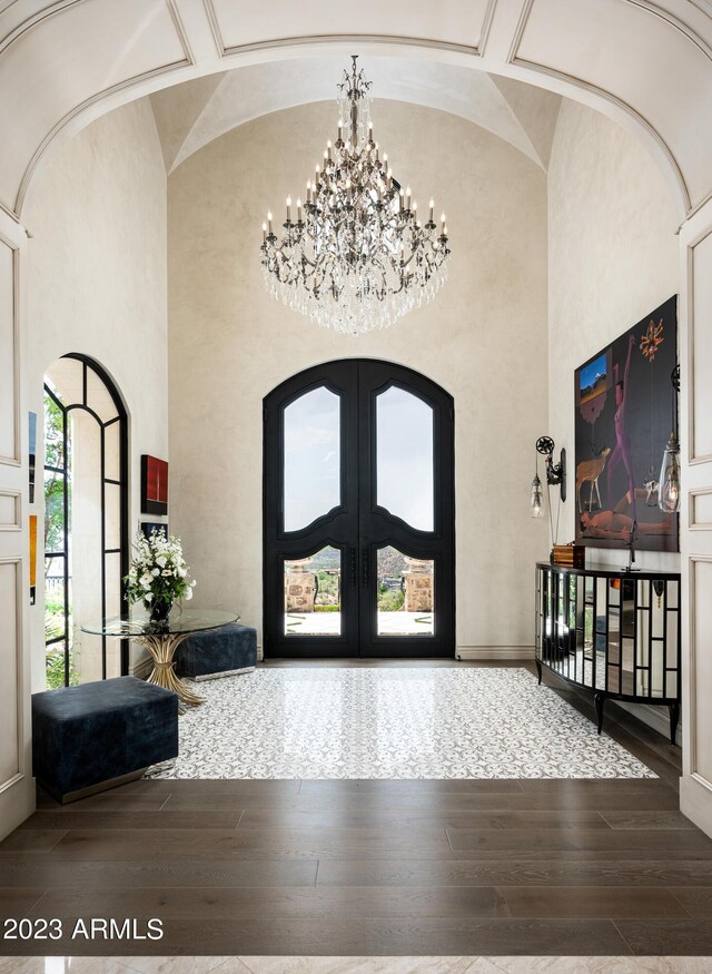 foyer entrance with high vaulted ceiling, wood-type flooring, a chandelier, and coffered ceiling