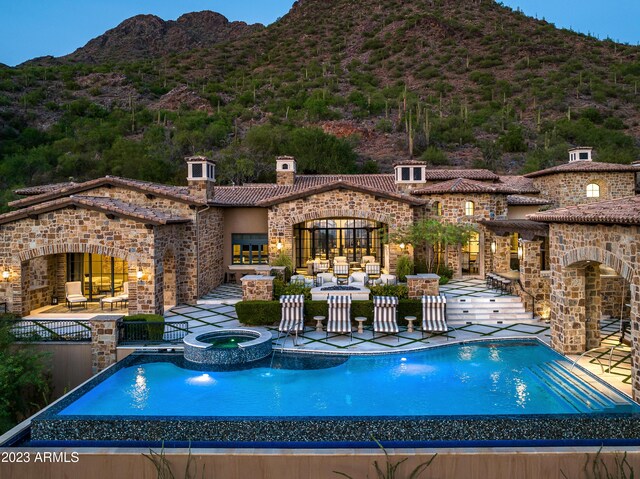 view of swimming pool featuring a mountain view, an in ground hot tub, and a patio