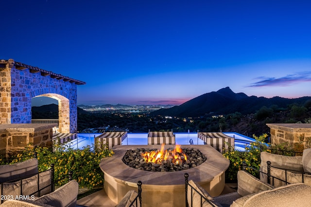 patio terrace at dusk featuring a mountain view and a fire pit