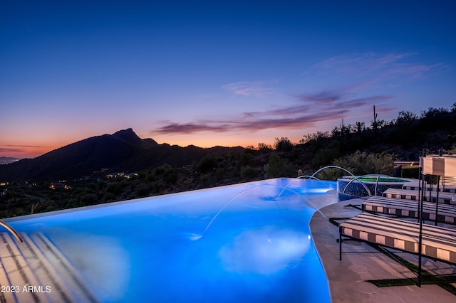 pool at dusk featuring a mountain view