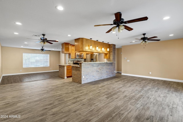 kitchen with kitchen peninsula, decorative backsplash, dark hardwood / wood-style floors, and appliances with stainless steel finishes