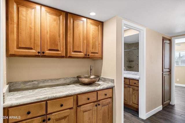 kitchen with light stone counters, dark hardwood / wood-style flooring, and sink