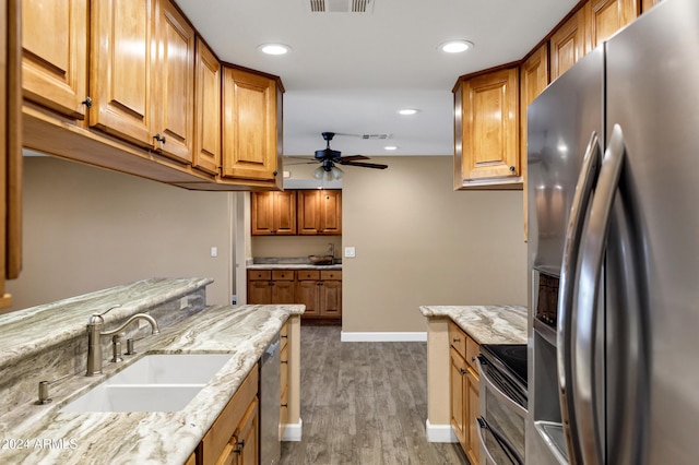 kitchen with ceiling fan, sink, stainless steel appliances, light stone counters, and dark hardwood / wood-style flooring