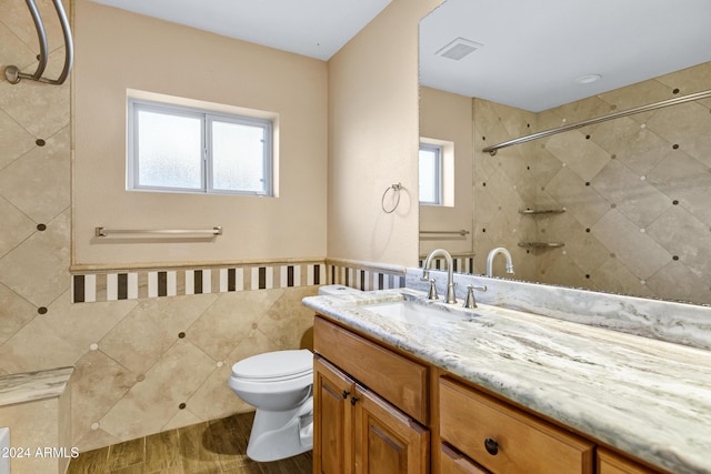 bathroom featuring wood-type flooring, vanity, toilet, and a healthy amount of sunlight